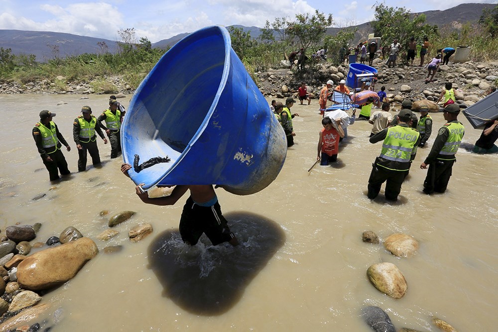 Hàng trăm người Colombia chạy khỏi Venezuela bằng cách băng qua sông Tachira. Họ vác theo các đồ dùng gia đình như giường, tủ lạnh và đệm. (nguồn: Ibtimes).