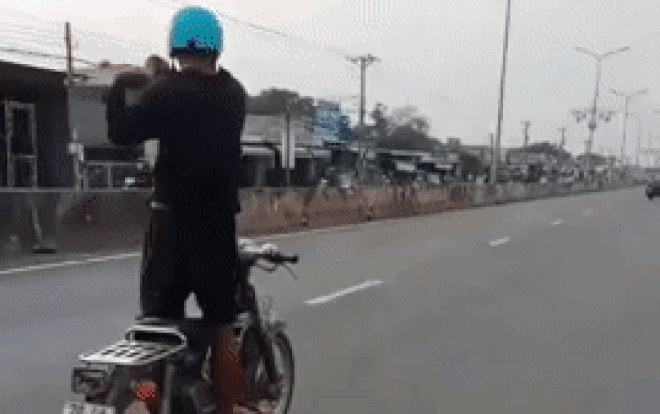 Người đàn ông đi xe máy giữa quốc lộ nhưng có hành động "kỳ lạ"