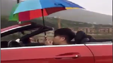 Thanh niên lái xe mui trần cầm ô che mưa