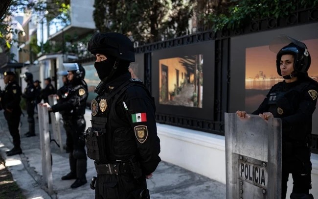 Các sĩ quan cảnh sát chống bạo động và các thành viên của đoàn cảnh sát ngoại giao đứng gác bên ngoài đại sứ quán Ecuador ở Mexico. (Ảnh: AFP)
