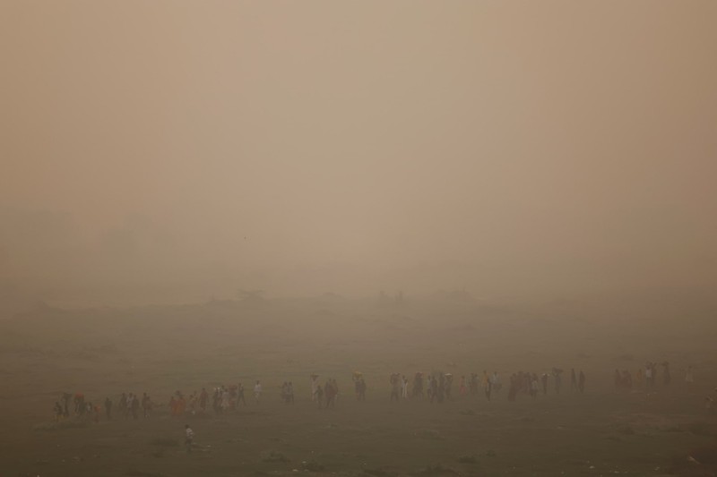 People walk on Kartavyapath near India Gate on a hazy morning in New Delhi