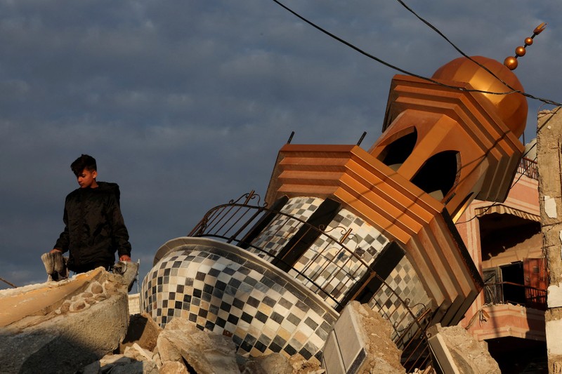 A boy walks near a minaret of a damaged mosque in Tayr Debba