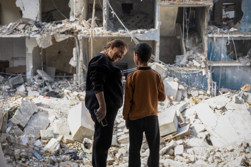 Nadine Amine, 50, talks to her son Jad Arouni, 10, as they stand inside their house damaged in an Israeli strike in Tyre