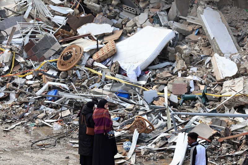 Women look at the rubble of a building in Beirut's southern suburbs