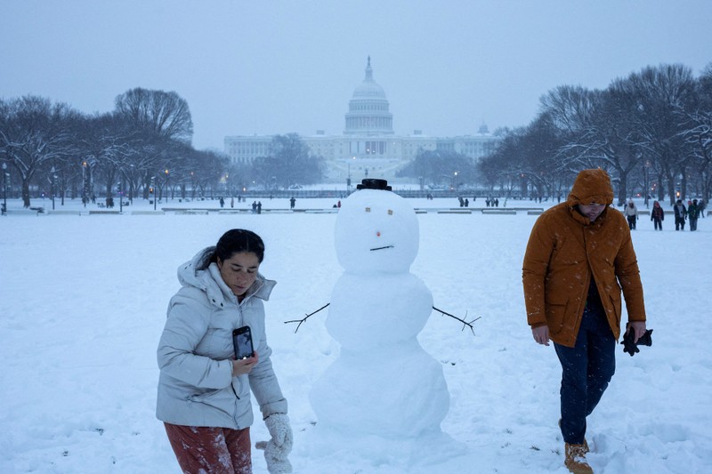 Mọi người đi bộ bên cạnh một người tuyết gần Điện Capitol Hoa Kỳ ở Washington