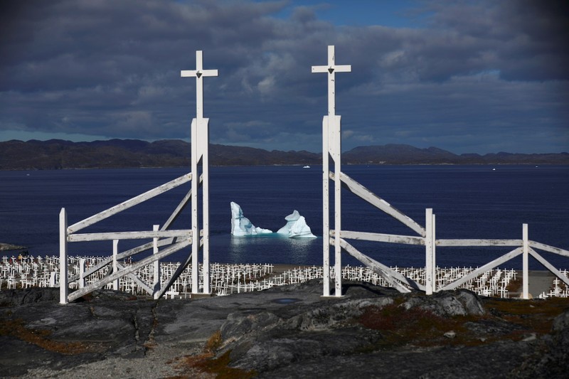 An iceberg is seen at the shore of a graveyard in Nuuk