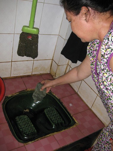 Bà Nguyễn Thị Tía lấy viên đá chặn bồn cầu ngăn chuột chui lên.