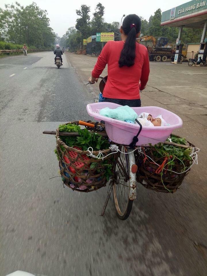 Me dap xe di ban rau cho con trong chau nhua day song